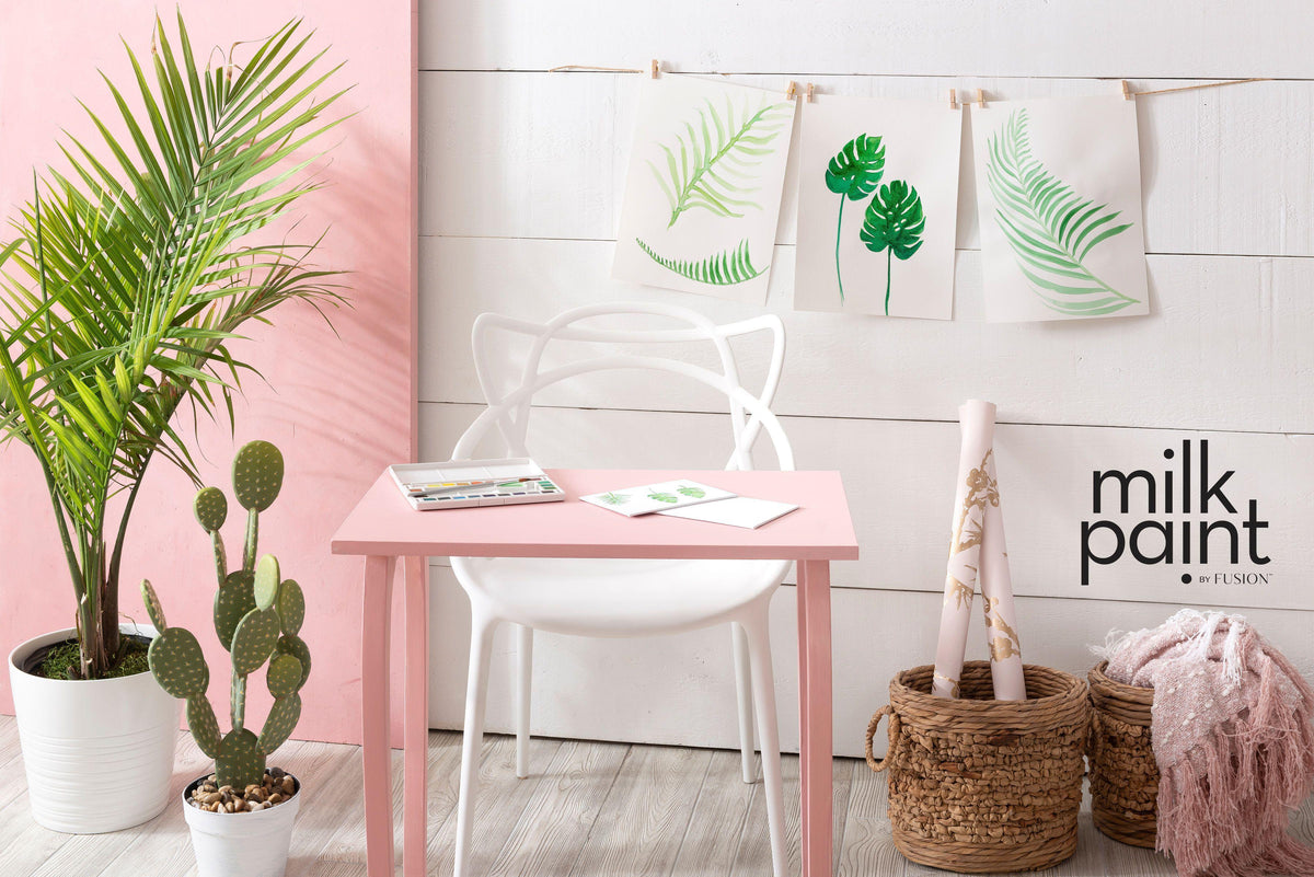 Pink desk painted in Fusion Mineral Paint Palm Springs Pink, shown with art supplies and plants.