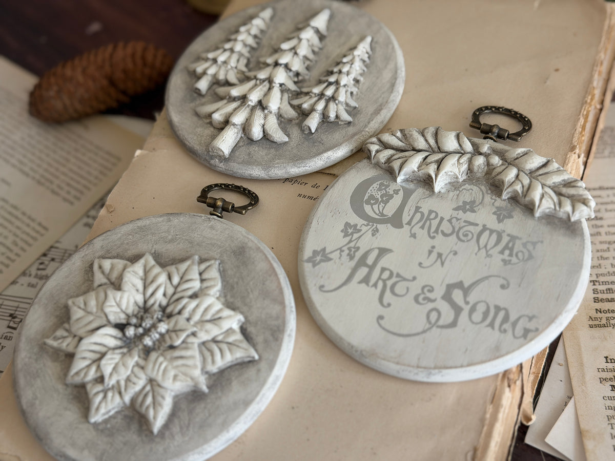 Set of 3 round ornaments featuring trees, poinsettia, and carol, created with I.O.D. Boughs of Holly (2026 Release) mould.