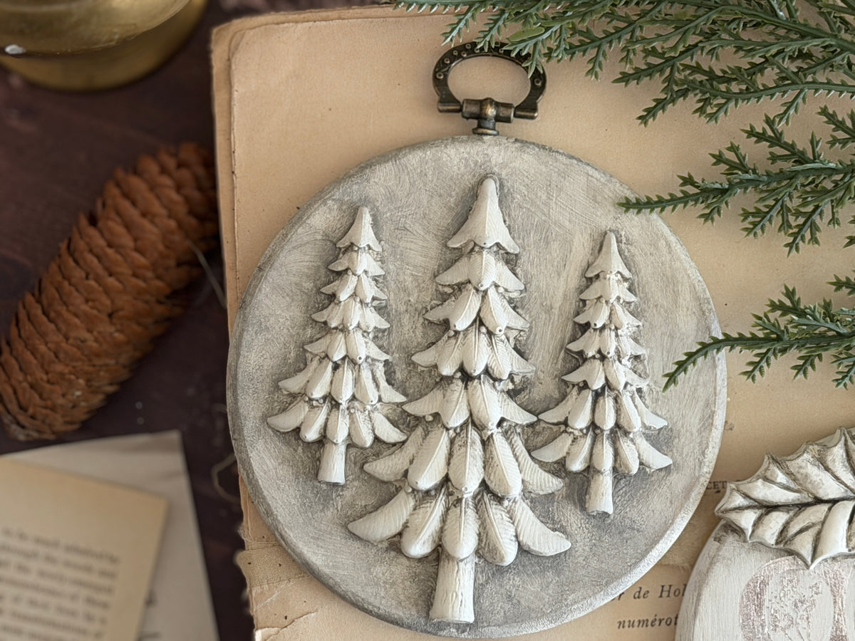 Round ornament featuring pine trees, greenery, and pine cone made with I.O.D. Boughs of Holly (2026 Limited Release) Mould.