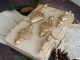Five gold ornaments made with I.O.D. Baubles Mould (2026 Limited Release) displayed on a book.