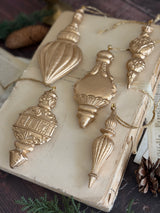Five gold baubles made with I.O.D. Baubles Mould (2026 Limited Release) displayed on an old book with pinecones.