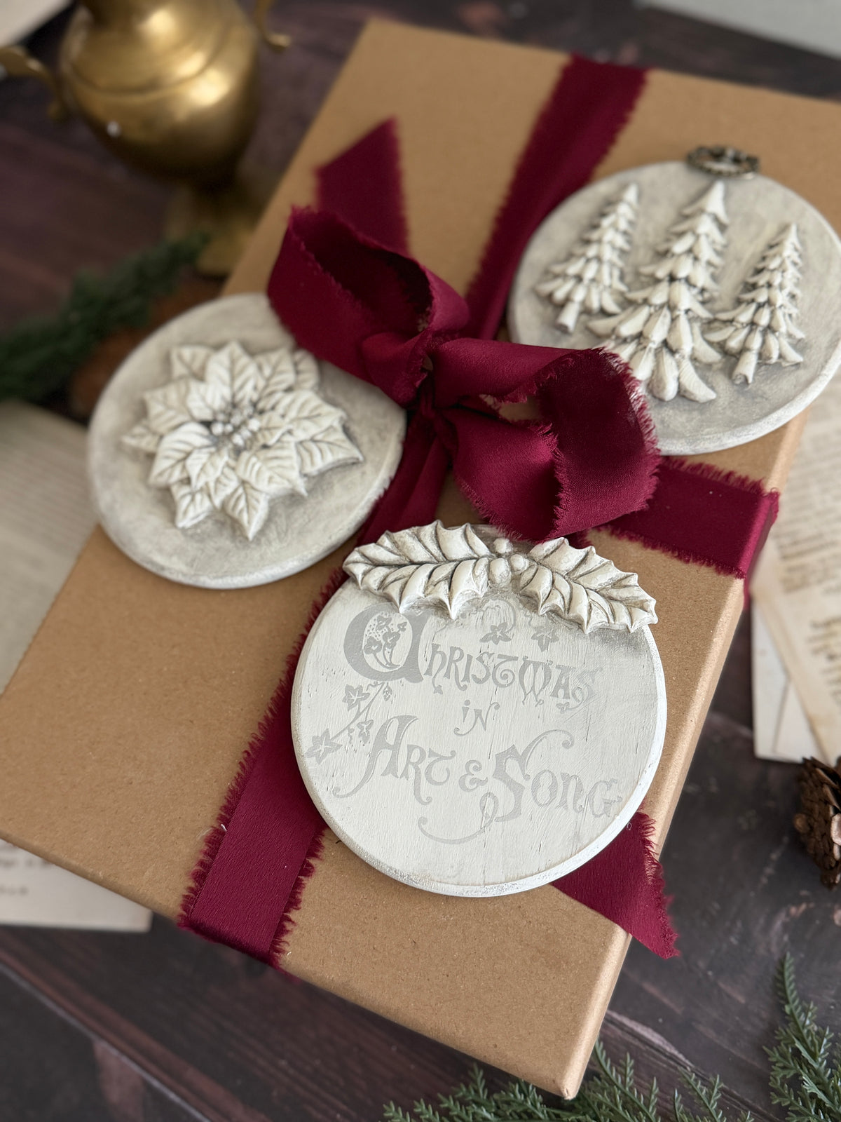 Brown gift box with burgundy ribbon, topped with I.O.D. Boughs of Holly (2026 Limited Release) holiday moulds.