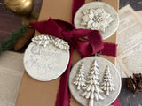 Brown paper-wrapped gift with red ribbon, adorned with I.O.D. Boughs of Holly (2026 Limited Release) ornaments.