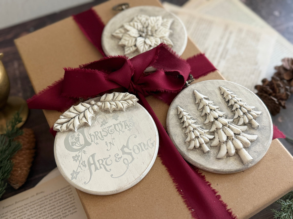Brown gift box decorated with Boughs of Holly by IOD ornaments and a burgundy ribbon.
