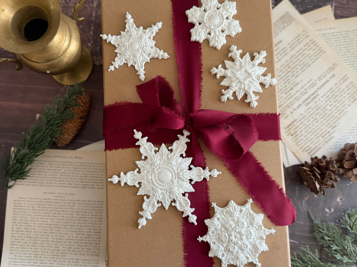 I.O.D. Snowflakes Mould 2026 Limited Release and red-ribbon gift displayed with pinecones and ornaments.