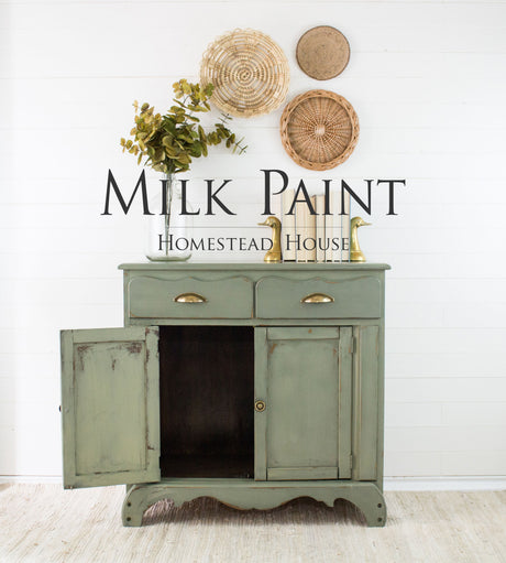 Green cabinet with open door, brass handles, and baskets, finished in Acadia Pear Milk Paint by Homestead House.