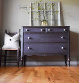Dark dresser painted with Old Fashioned Milk Paint’s Adelaide, vase with green branches on top, next to a chair.