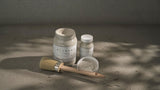 Three jars of Alabaster Alchemy Paint by Fusion with a wooden brush on concrete.