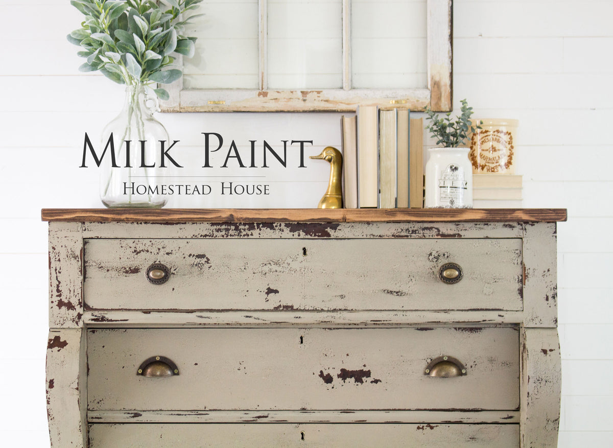 Distressed dresser in Algonquin Milk Paint by Homestead House, styled with books and greenery on top.