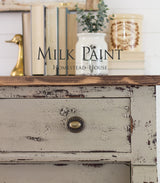 Dresser painted with Algonquin Milk Paint, brass knob, books, ceramic jar, and brass duck accent on top.