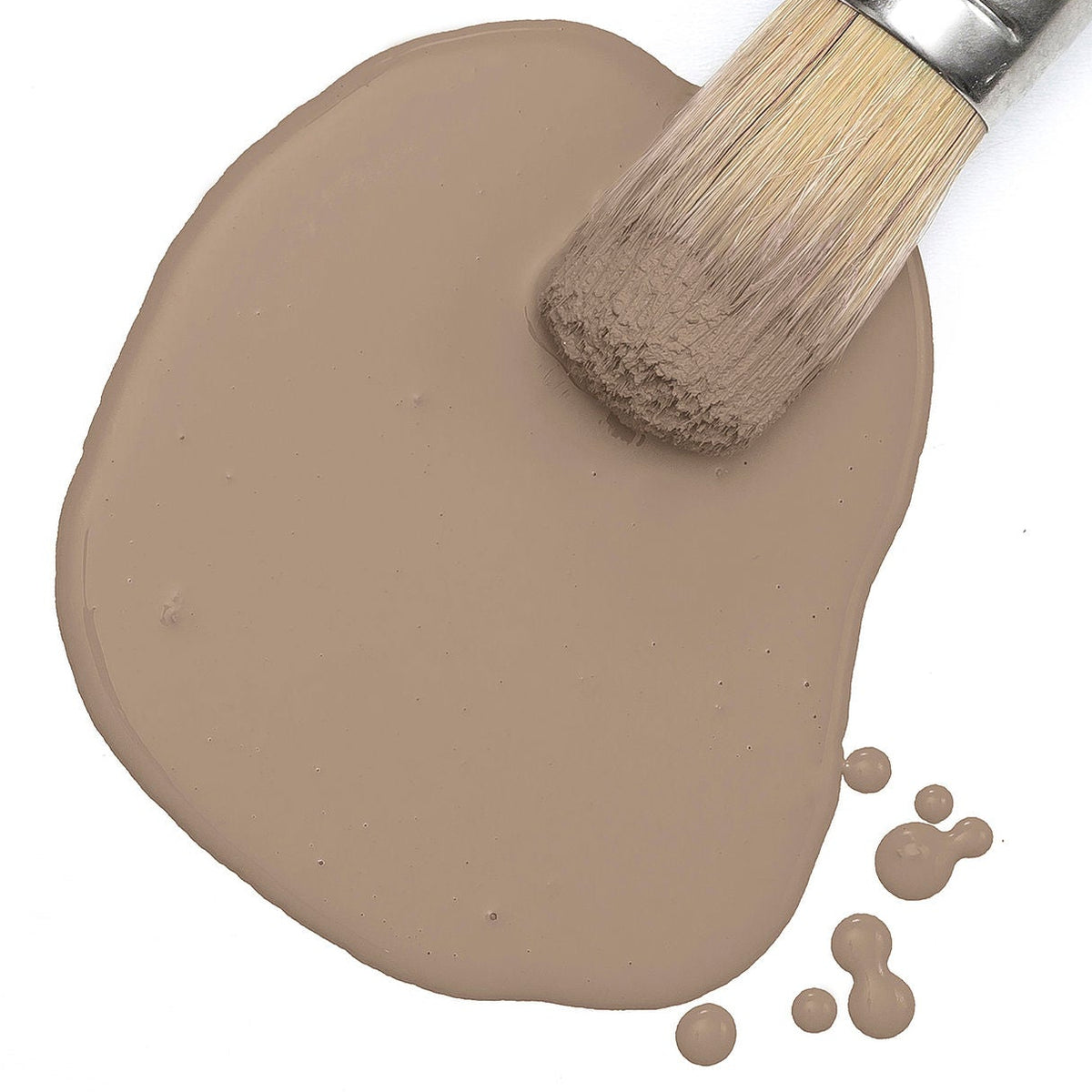 Paintbrush on spilled Fusion Almond Latte Milk Paint with visible droplets nearby.