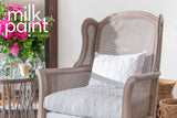 Wingback chair with white cushions next to round table; “Almond Latte Milk Paint by Fusion” text above.