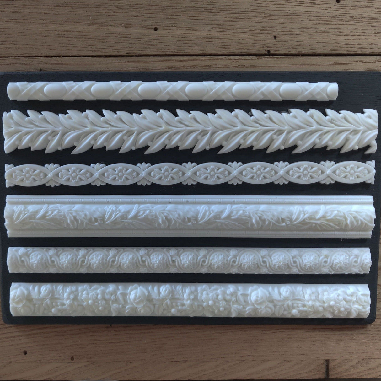 Six white Notions Amazing Casting Resin trim borders arranged on a plain black background.
