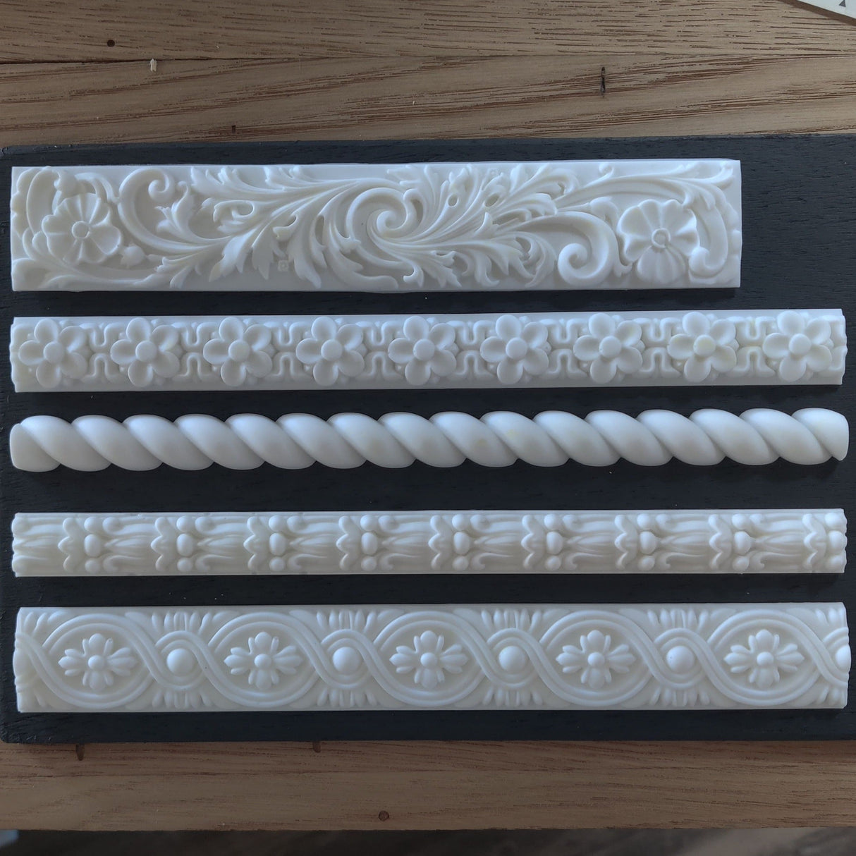 Five Notions Amazing Casting Resin (White) moldings displayed on a wooden surface.