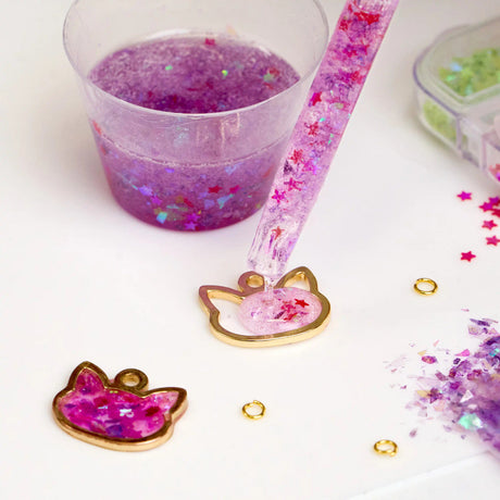 Pipette dispensing pink glitter resin into a cat mold with Notions Amazing Clear Cast Epoxy.