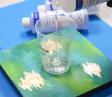 Amazing Clear Cast +Plus Epoxy by Notions being poured into a cup, with product bottles visible in the background.
