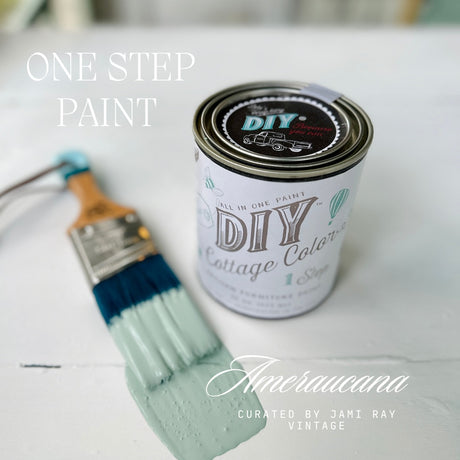 Paintbrush with blue and green paint beside DIY Paint Co. Ameraucana DIY Cottage Color jar with built-in top coat.