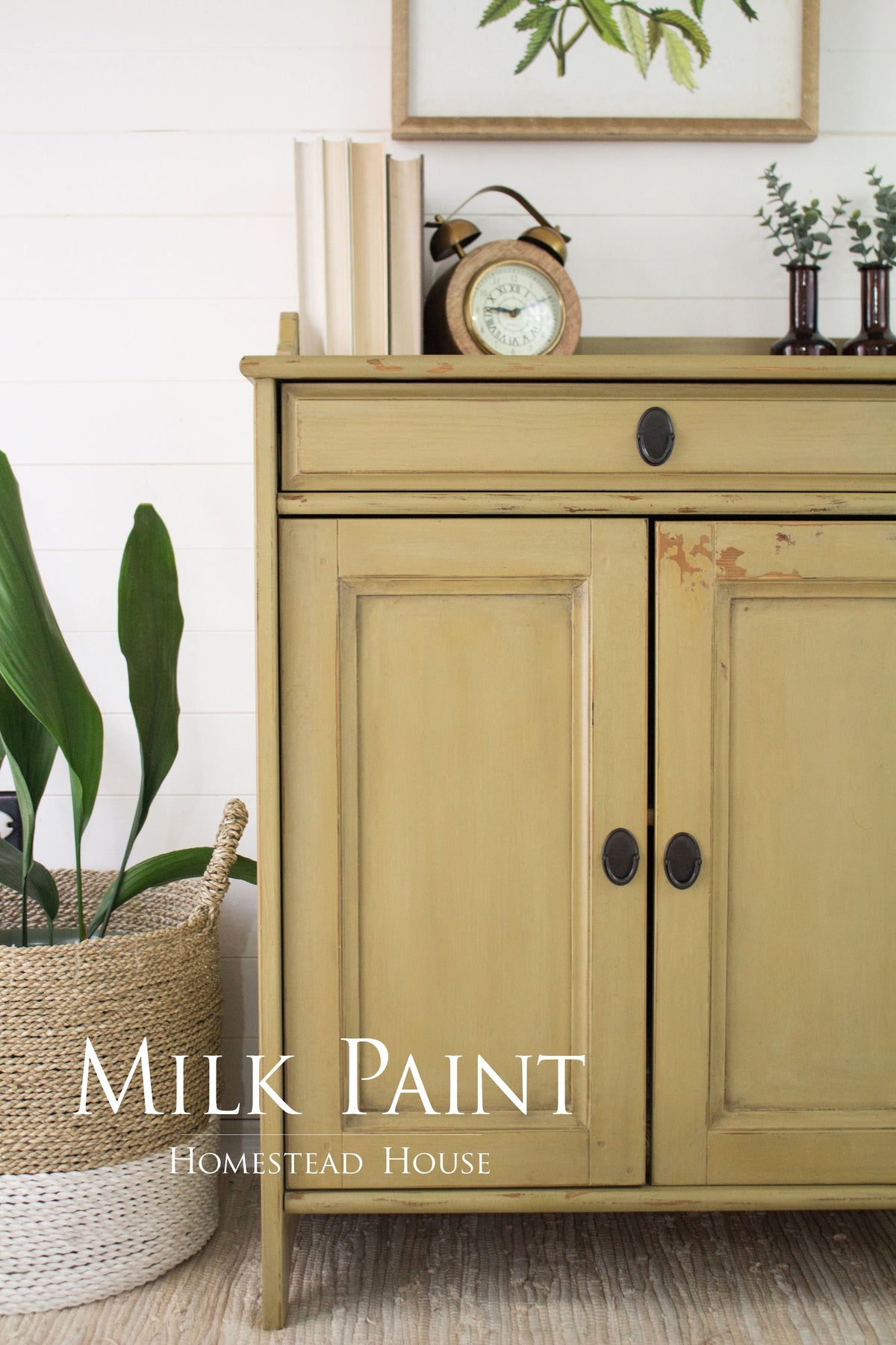 Sideboard in Antique Gold Milk Paint by Homestead House, displayed with books, a clock, and plants on top.