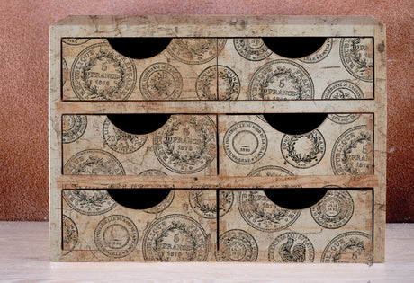 Small wooden cabinet with six drawers, decorated with IOD Antiquities Stamp by Iron Orchid Designs.