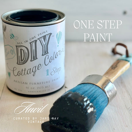 Open can of Anvil DIY Cottage Color paint by DIY Paint Co. with a blue-bristled brush beside it.