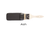 Paintbrush dipped in Fusion Mineral Paint Ash, a dark charcoal grey acrylic, on plain white background.