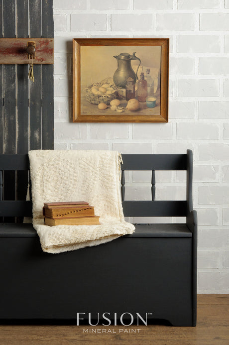 Charcoal grey bench painted with Ash by Fusion Mineral Paint, with books and a blanket placed on top.