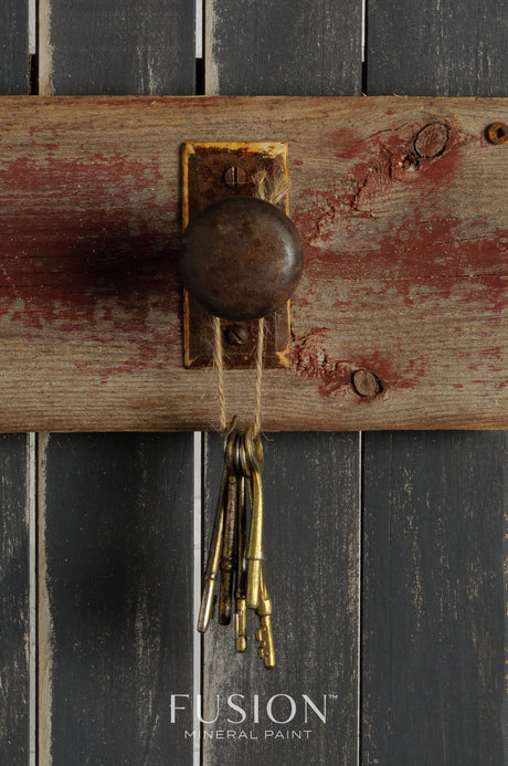 Rusty doorknob and old keys on wood, with Fusion Mineral Paint in Ash (dark charcoal grey) visible underneath.
