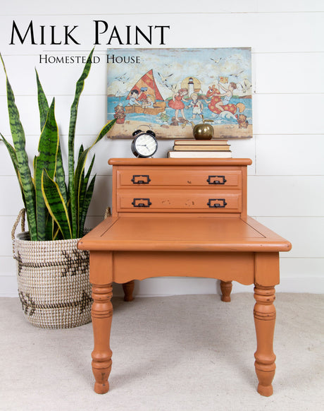 Orange wooden table painted with Homestead House Autumn Leaves Milk Paint; decor, plant, art, and “Milk Paint” text visible.