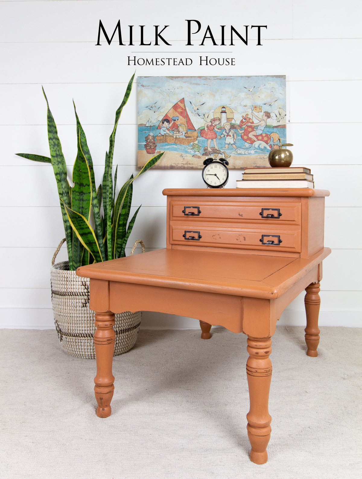 Vintage side table in Homestead House Autumn Leaves Milk Paint with drawers, topped with a plant, books, and clock.