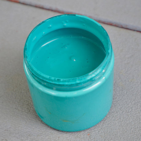 Open jar of Azure DIY Cottage Color paint by DIY Paint Co. on a light gray surface.