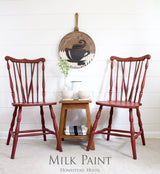 Two Homestead House Barn Red chairs beside a tea table, with COFFEE wall decor above.