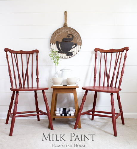 Two Homestead House Barn Red chairs beside a tea table, with COFFEE wall decor above.