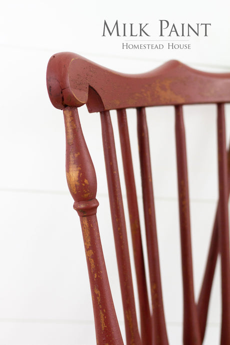 Worn red chair with text: Barn Red Milk Paint by Homestead House.