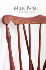 Red wooden chair with chipped Barn Red Milk Paint by Homestead House, shown beneath product text.