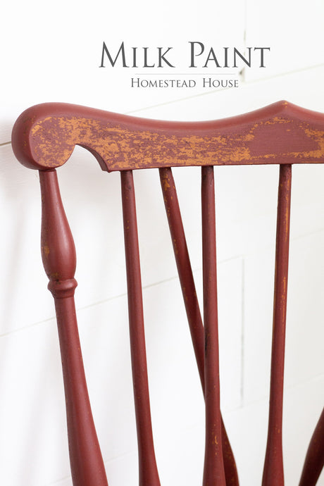 Red wooden chair with chipped Barn Red Milk Paint by Homestead House, shown beneath product text.