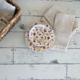 Two patterned plates, beige napkins, and a basket on a table stamped with Barnwood Planks by I.O.D.