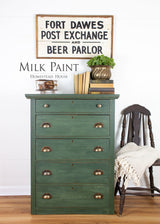 Green dresser painted in Homestead House Bayberry Milk Paint with brass handles, books, and a plant displayed on top.