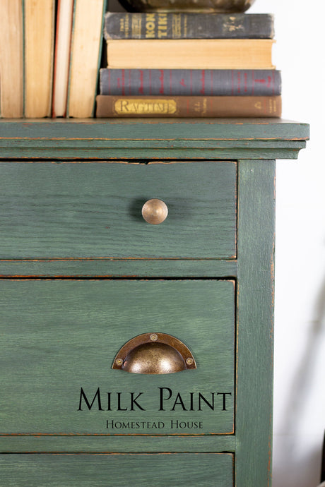 Bayberry Milk Paint green dresser by Homestead House with brass handles, topped with stacked books.