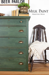 Bayberry Milk Paint dresser by Homestead House with brass handles, books, and a plant on top.