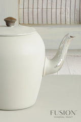 White vintage teapot with chipped spout; Fusion Mineral Paint “Bedford” shown in lower right corner.
