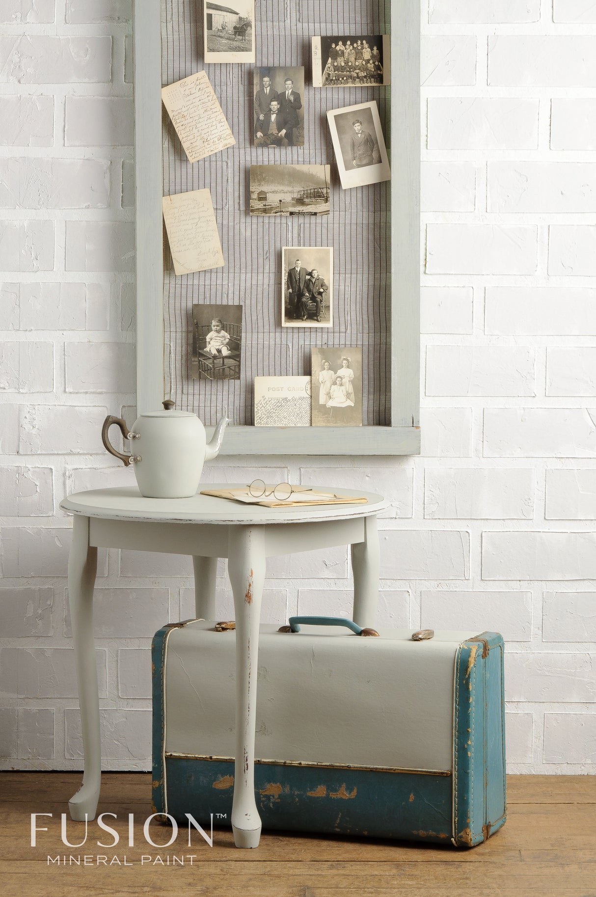 Small table with teapot, suitcase, and photos on Bedford Fusion Mineral Paint by Fusion Mineral Paint background.
