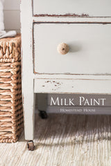 Distressed white drawer with woven knob, next to a wicker basket; Homestead House Bedford Milk Paint shown.