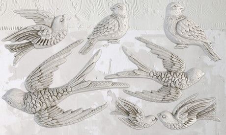 Eight white birds made with Birdsong Mould by I.O.D. arranged on a textured white wall.