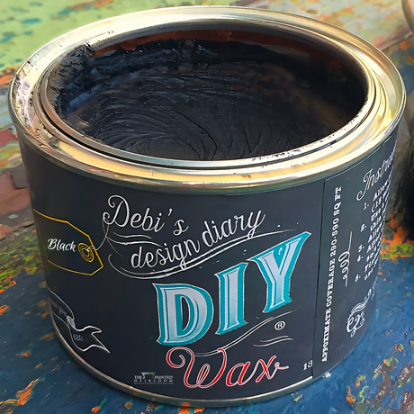 Open can of Black DIY Wax by DIY Paint Co. on a paint-splattered surface.