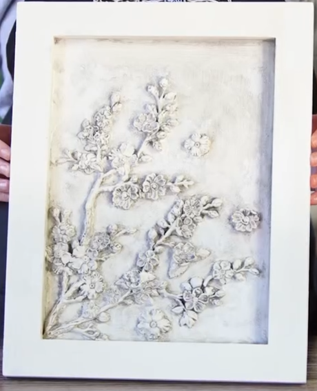 I.O.D. Blossom Mould art with raised floral branch design on a textured neutral background, shown held upright.