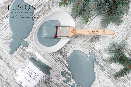 Blue Pine Fusion Mineral Paint jar with paintbrush on white wood, matte finish, pine branches nearby.