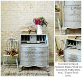A Bluebird desk in Old Fashioned Milk Paint with French text, paired with fresh flowers and a chair.