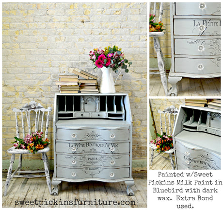 A Bluebird desk in Old Fashioned Milk Paint with French text, paired with fresh flowers and a chair.
