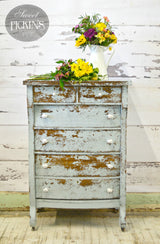 Distressed Bluebird dresser by Old Fashioned Milk Paint with white knobs, topped with yellow and purple florals.