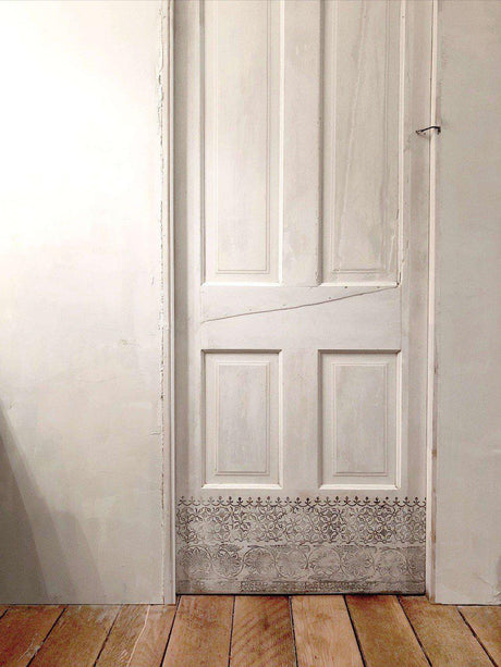 White carved door on wood floor, shown as a display surface for I.O.D. Bohemia Stamp (Retired) by Iron Orchid Designs.